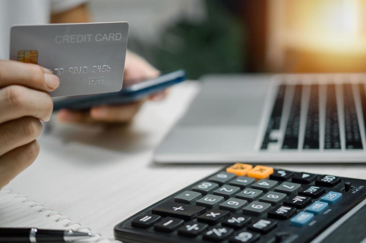 A person holding credit card while working on mobile